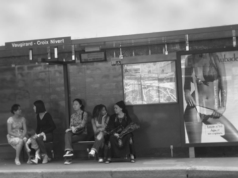 Photographie par Arslan (2016) provenant de Flickr, représentant des femmes attendant à un arrêt de bus où est affiché le corps fractionné d’une femme à but publicitaire.