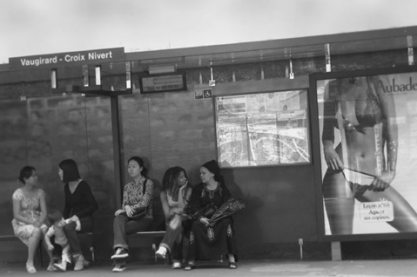 Photographie par Arslan (2016) provenant de Flickr, représentant des femmes attendant à un arrêt de bus où est affiché le corps fractionné d’une femme à but publicitaire.